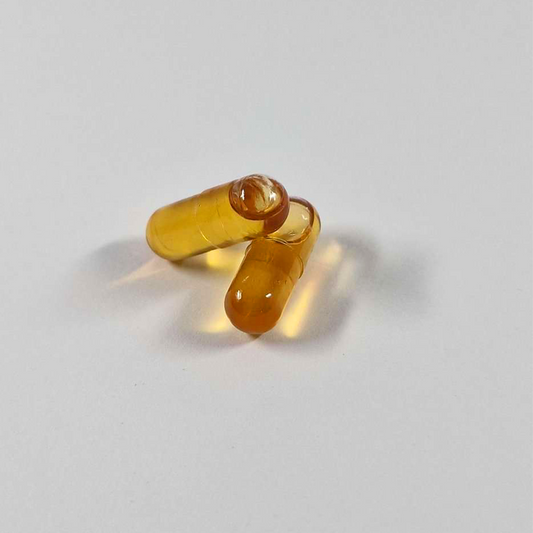 Trois gélules CBD ambrées translucides, forme ovale