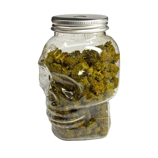 Bocal en verre scellé en forme de crâne, fleurs CBD vertes, vue de côté
