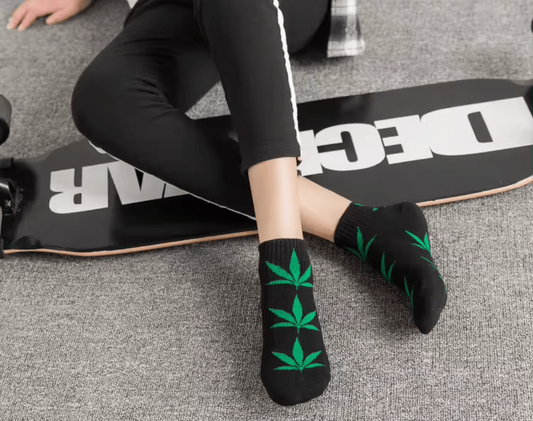 Paire de chaussettes noires à feuilles de cannabis vertes, portées.