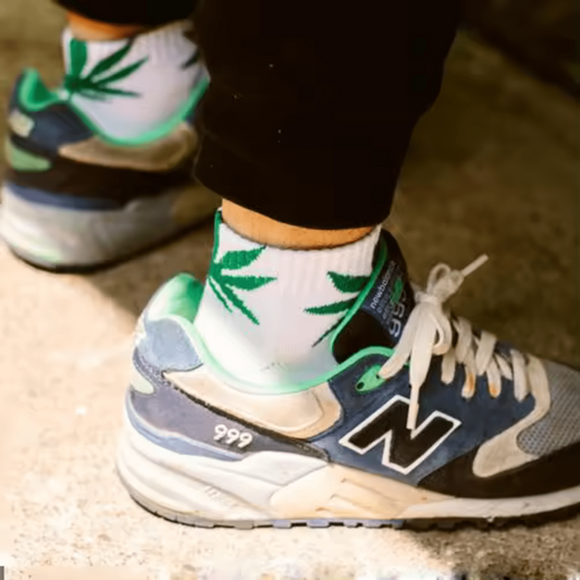 Chaussettes blanches à motif feuilles de cannabis vertes, portées avec baskets