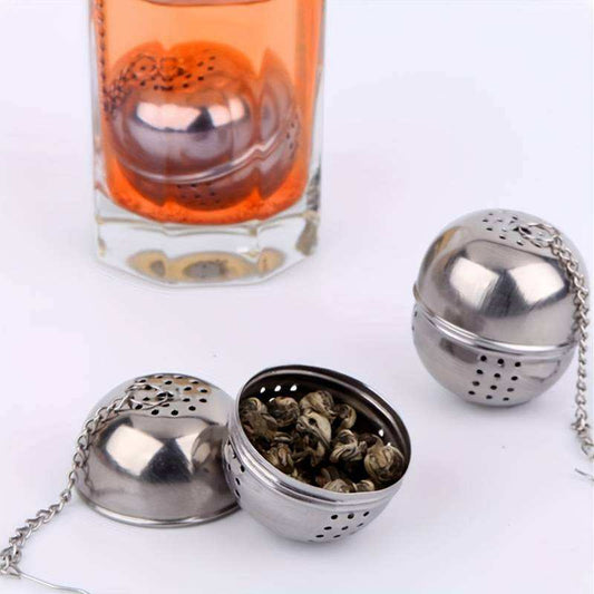 Infuseur à thé boule en acier inoxydable, moitié ouverte avec feuilles de thé et chaîne.