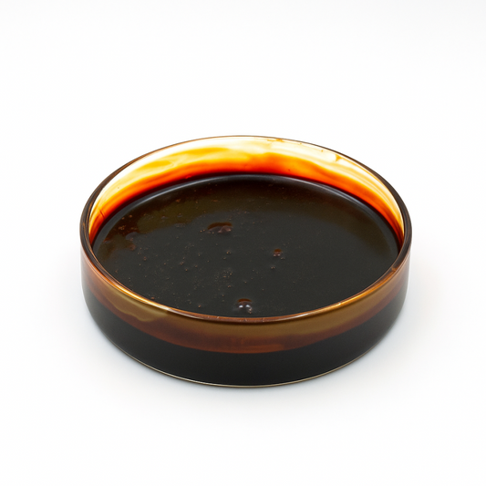Pot de CBD brut avec surface de liquide brun foncé, bord ambré