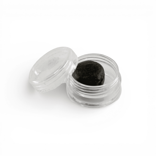 Petit pot de crème CBD, couvercle ouvert et pastille de résine noire