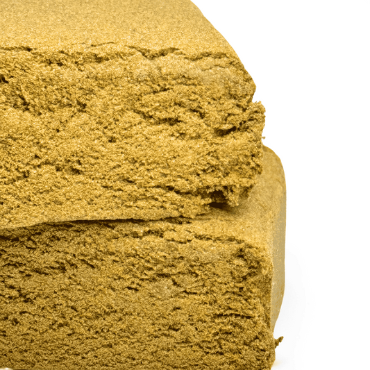 Bloc de résine CBD jaune d’or, texture friable, vue rapprochée sur la coupe